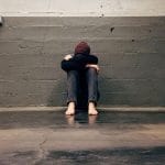 Žalosten moški sedi ob steni