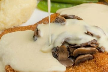 Ocvrt zrezek z gobovo smetanovo omako in krompirjevim pirejem